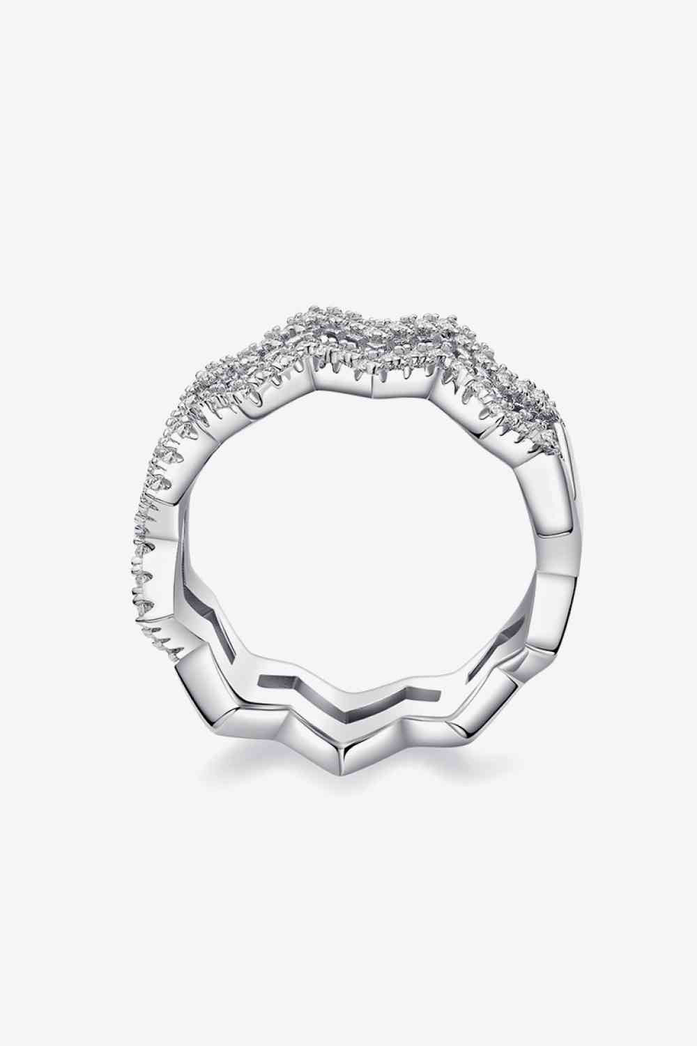 A silver ring with an intricate design featuring small sparkling diamonds arranged in a wave pattern on the top half. The band has a slightly angular, faceted appearance, adding a modern touch to this fashion-forward jewelry piece. The background is plain white. This is the Adored Moissanite Zigzag Stacking Rings by Marianela's Exclusive Shop, LLC.