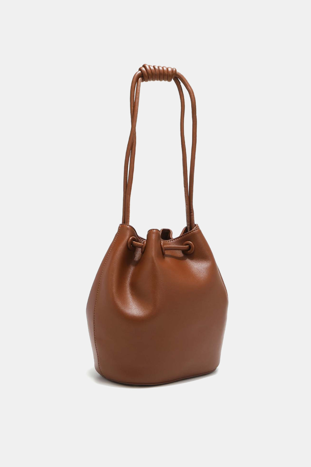 The Nicole Lee USA Amy Studded Bucket Bag from Marianela's Exclusive Shop, LLC features a brown pebbled vegan leather design with a drawstring and snap button closure. The extended handles are twisted at the top, creating a distinctive knotted look. It boasts a smooth, polished finish and is displayed on a flat surface against a plain white background.