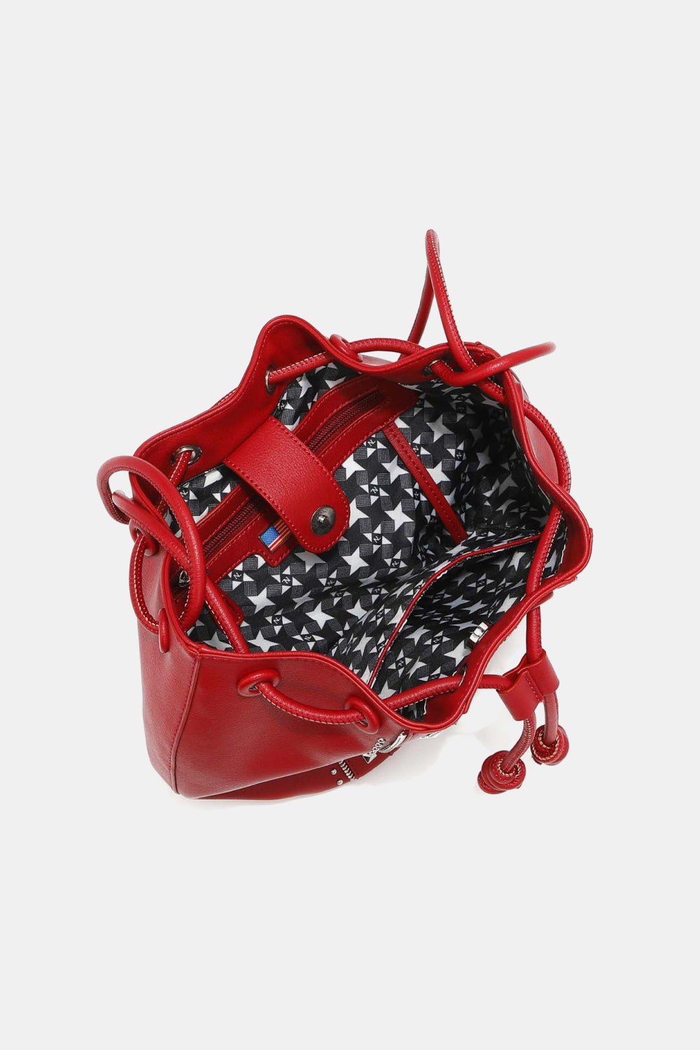 The Nicole Lee USA Amy Studded Bucket Bag from Marianela's Exclusive Shop, LLC features a red pebbled vegan leather exterior and an open top that reveals a stylish black and white patterned interior lining. The bag is equipped with a secure drawstring closure and red straps. Inside, you'll find a small pocket for essentials, while the top closure flap is accented with button and stud detailing for an added touch of flair.