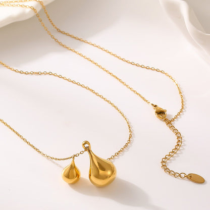 The Elysian Gold Water Drop Necklace from Marianela's Exclusive Shop showcases two exquisite water drop-shaped pendants on a delicate 18K gold plated chain, elegantly presented against a light background.