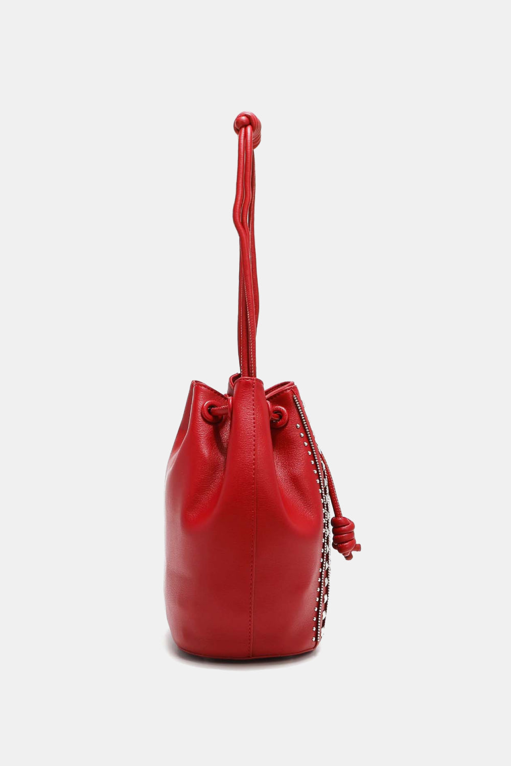 Introducing the Nicole Lee USA Amy Studded Bucket Bag from Marianela's Exclusive Shop, LLC. This red pebbled vegan leather bucket bag, viewed from the side, showcases a secure drawstring closure with a decorative knot at the top. It features a smooth finish and a single handle, with edges accented by small studs. The bag is displayed against a plain white background.