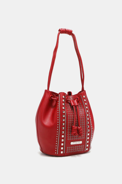 The Nicole Lee USA Amy Studded Bucket Bag from Marianela's Exclusive Shop, LLC is a stylish red pebbled vegan leather bag featuring silver stud detailing arranged vertically and a secure drawstring closure. The single handle is looped at the top, and the bag stands upright against a plain white background.