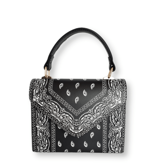 A stylish black Bandana Print Crossbody Bag with a paisley pattern in white from Marianela's Exclusive Shop, LLC. The bag has a single black handle attached by small gold-colored clasps and features a structured, rectangular design with a flap closure. Additionally, it includes a versatile detachable metal chain strap for added convenience.
